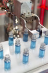 Robotic mechanical arm is manipulating chemical tubes full with blue substance in a medical laboratory during a test.